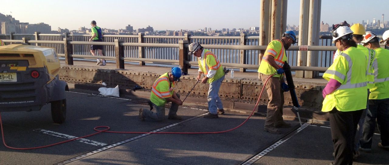 Constructions workers on bridge applying joint sealant