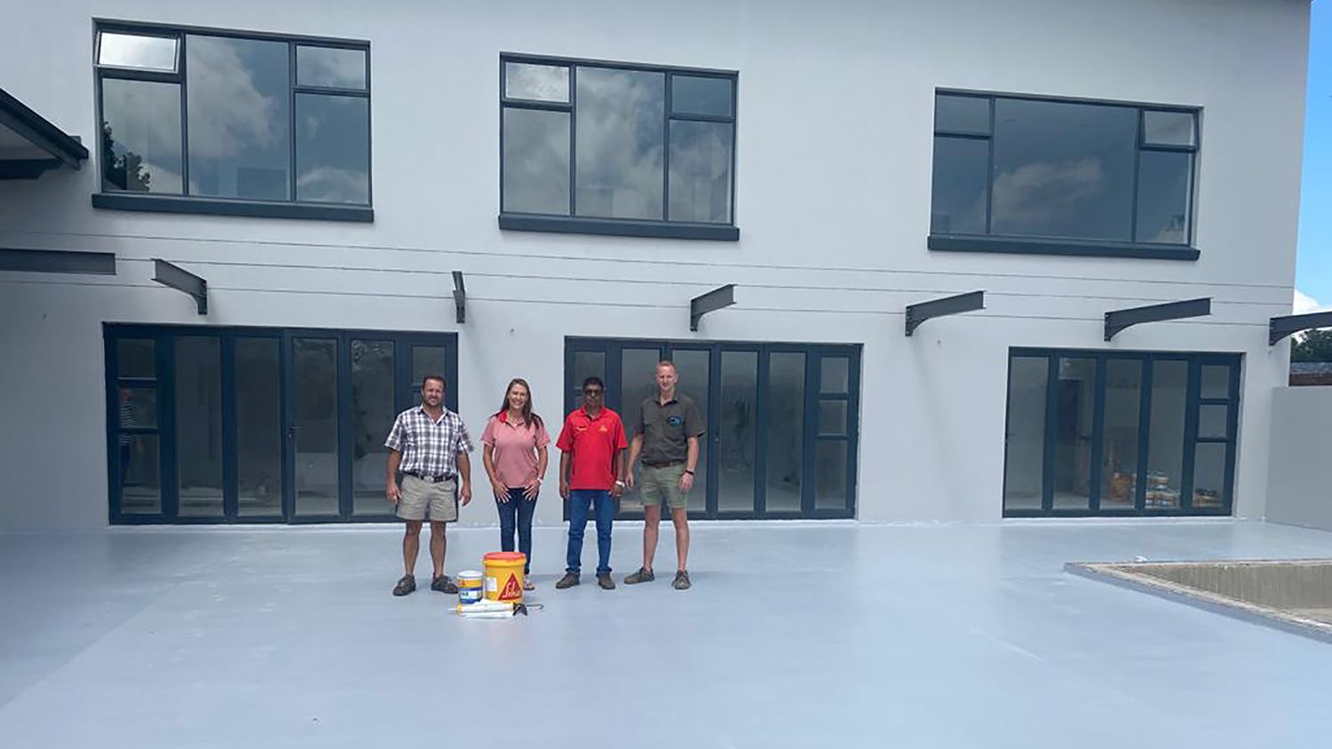 Sika staff and contractors at newly, acrylic, liquid-applied waterproofing flat roof of a house in Secunda. 