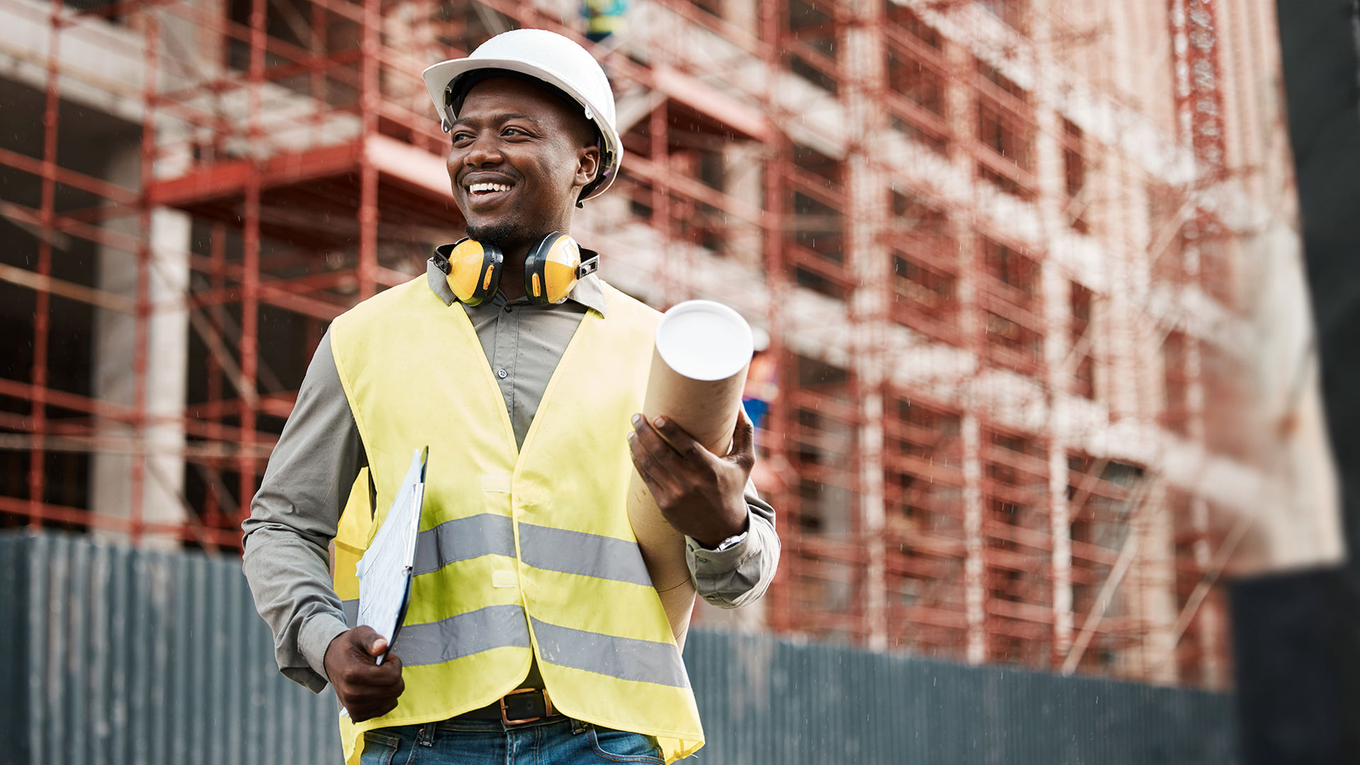 Construction worker holding plans and coffee
