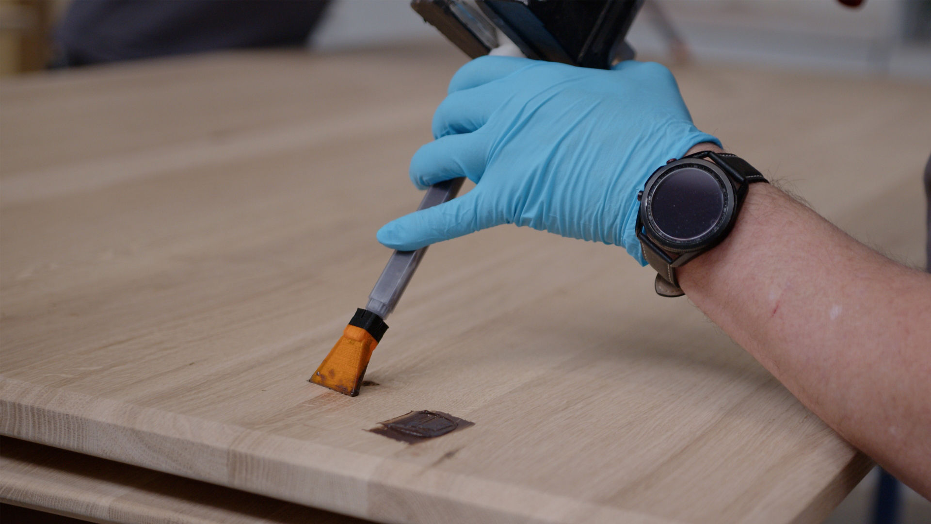Person applying adhesive to wooden surface with brush
