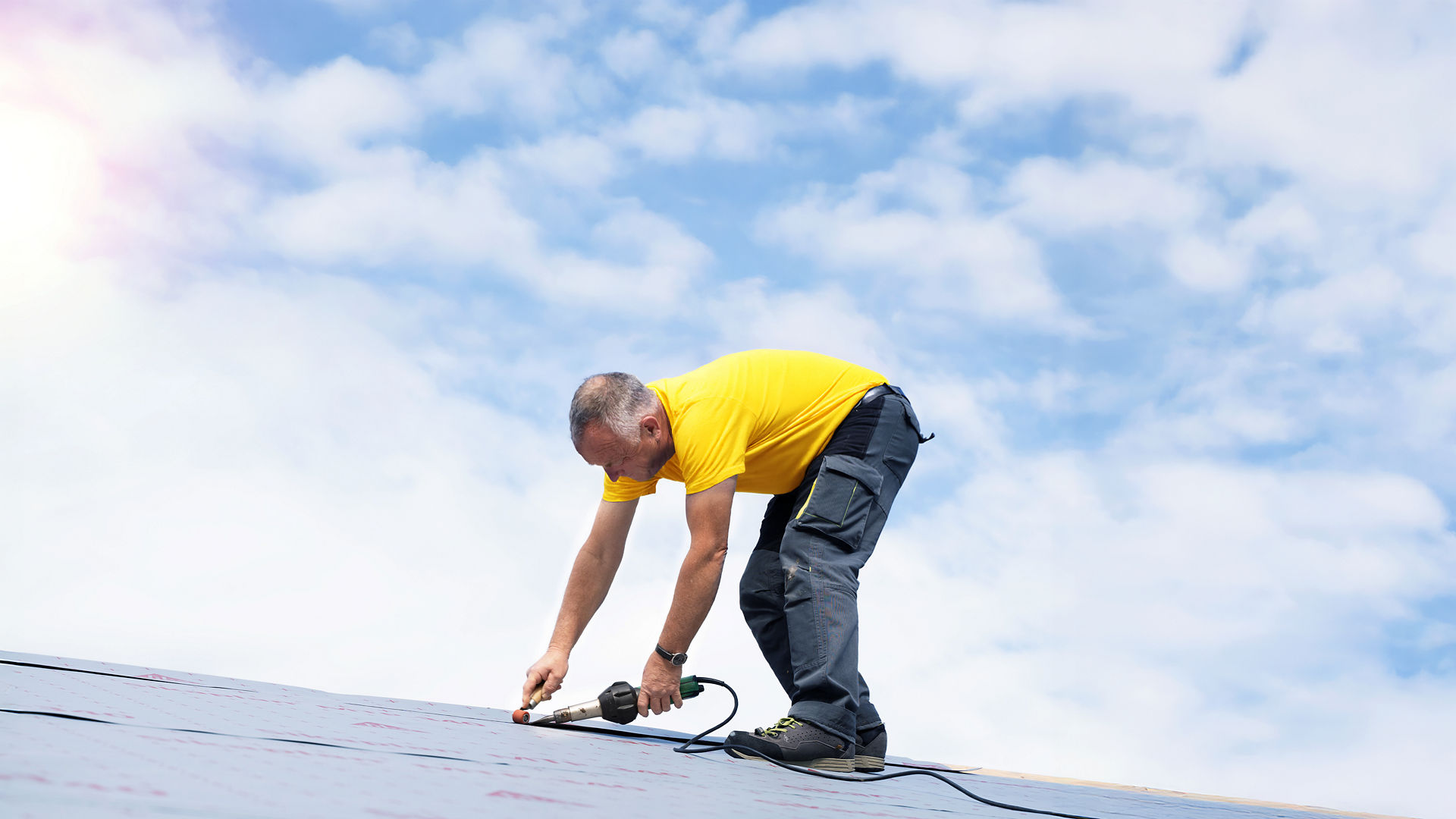 Man in yellow shirt working on roof