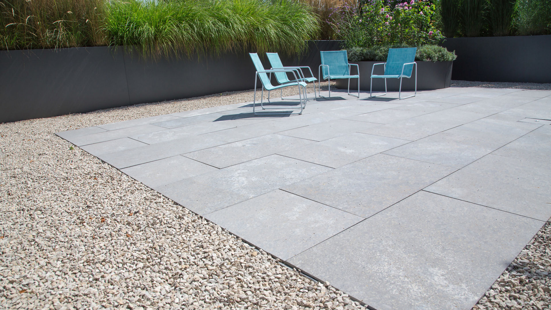 Modern patio with blue chairs and stone tiles