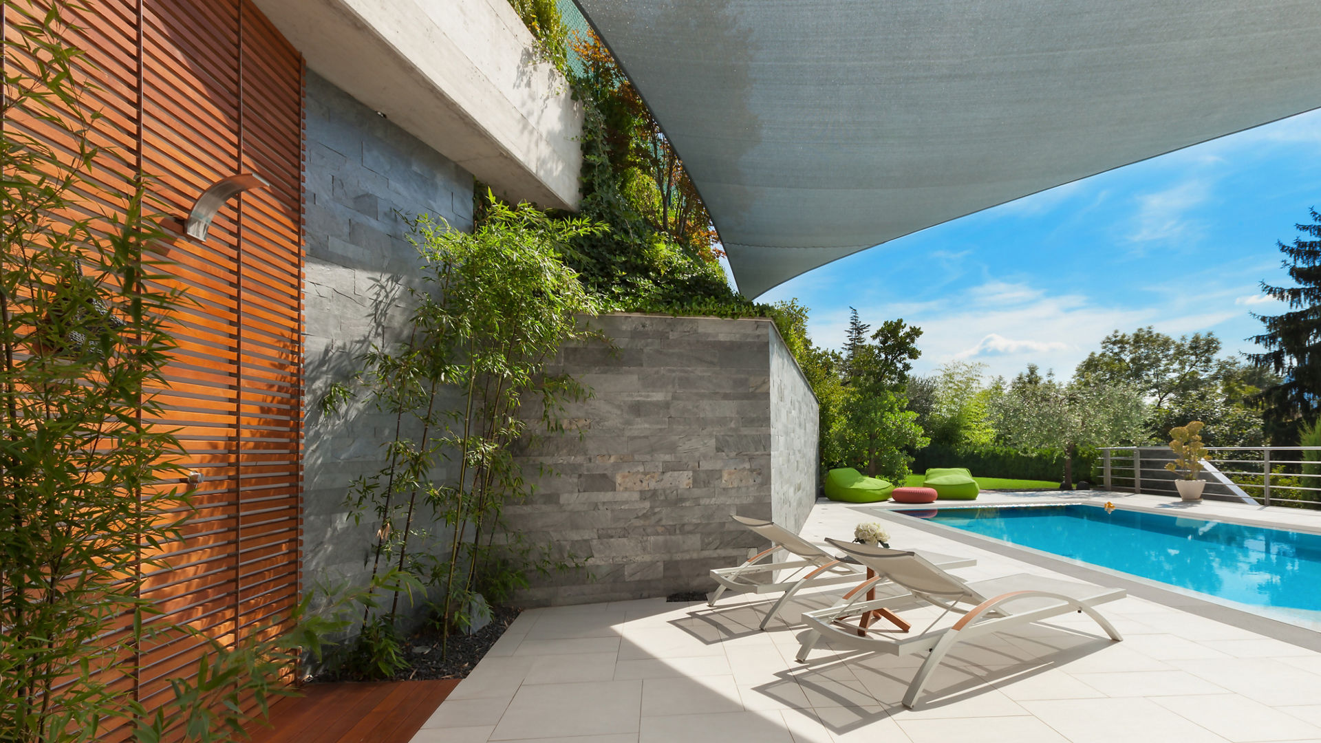 Modern poolside patio with lounge chairs and shade