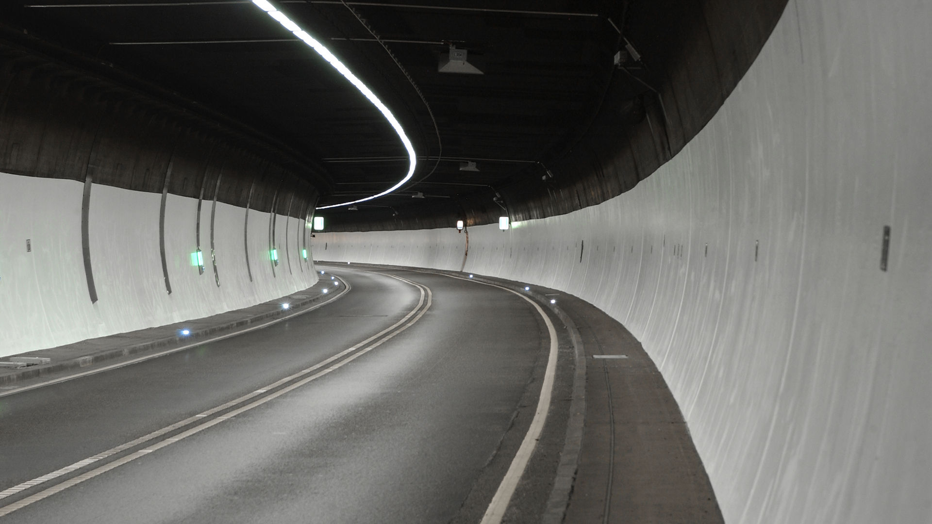Curved empty road tunnel with illuminated ceiling