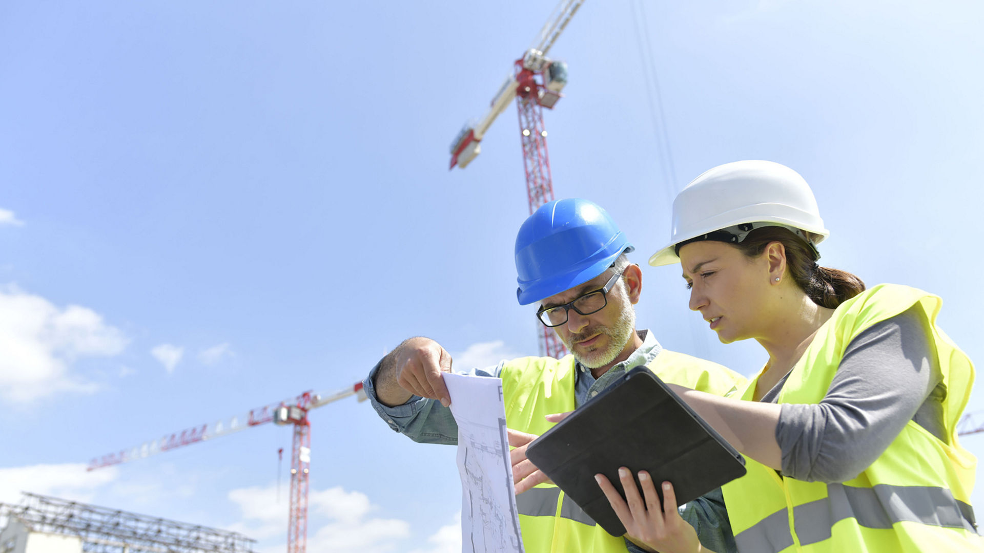 Bauleiter sehen sich auf der Baustelle Pläne an und sprechen darüber.