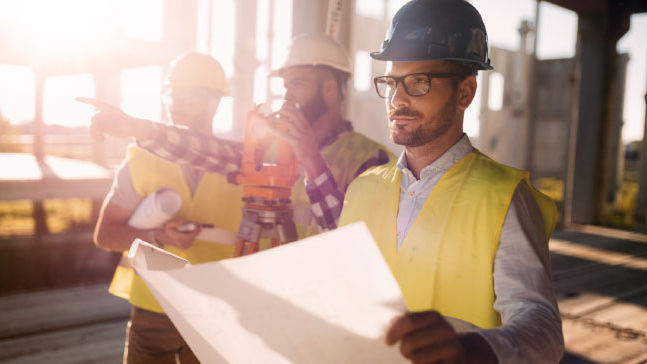 Construction workers reviewing site plans outdoors