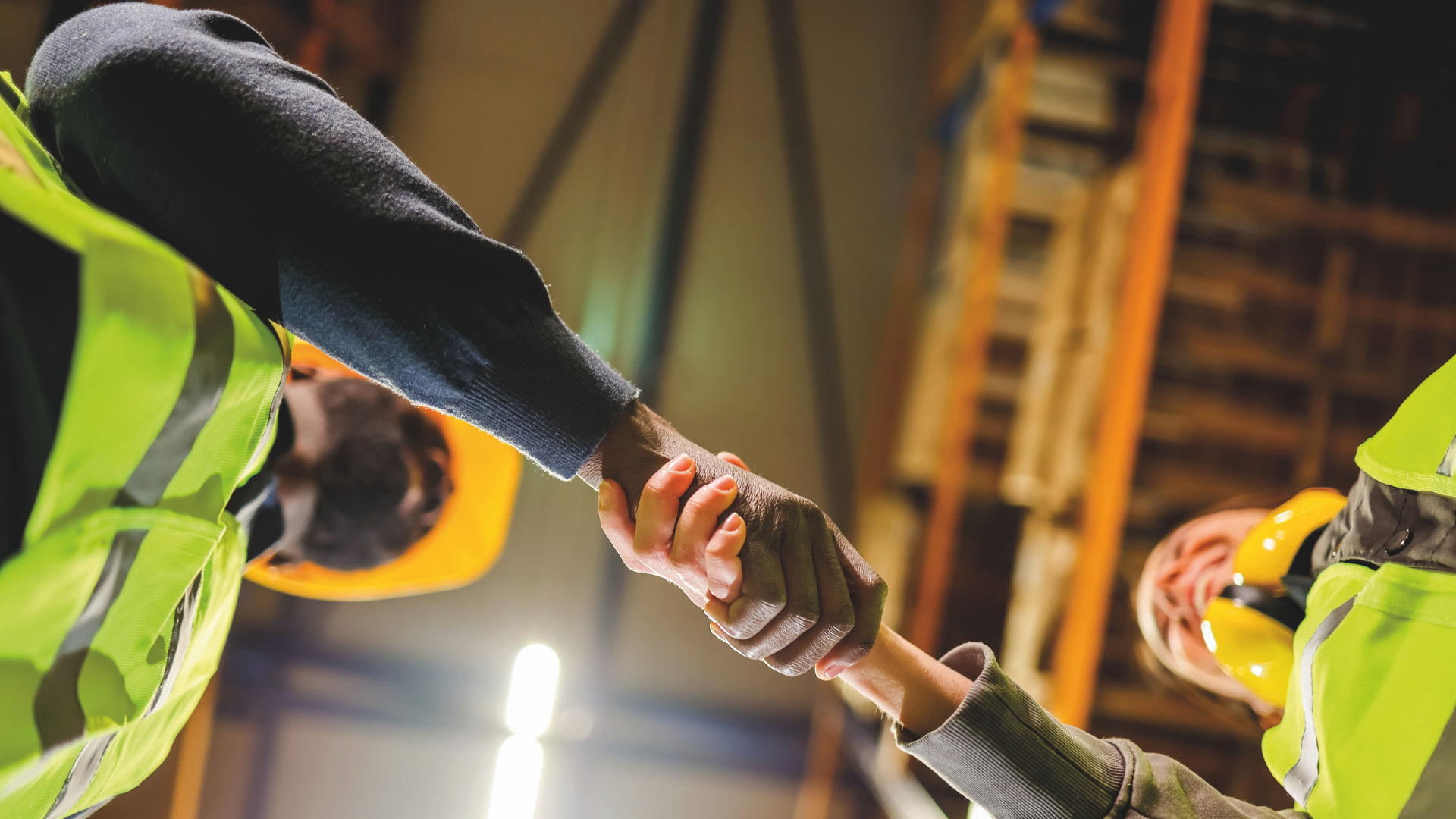 Construction workers shaking hands in warehouse setting