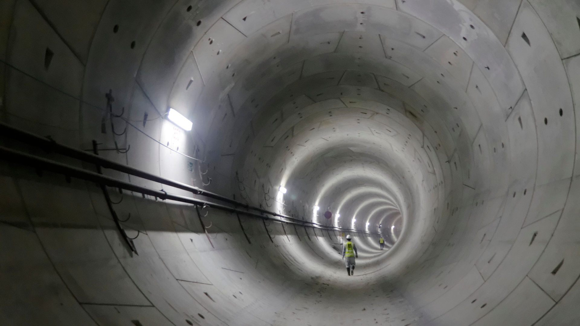 Worker walking inside illuminated concrete tunnel
