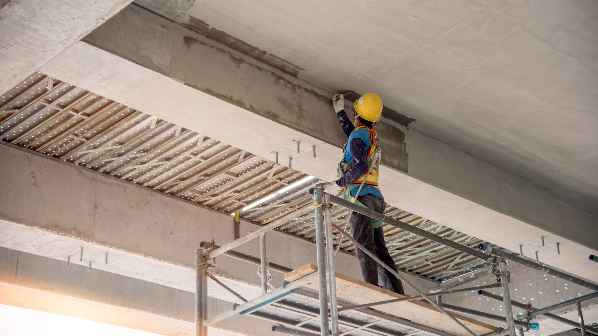 Construction worker applying concrete repair mortar to bridge beam