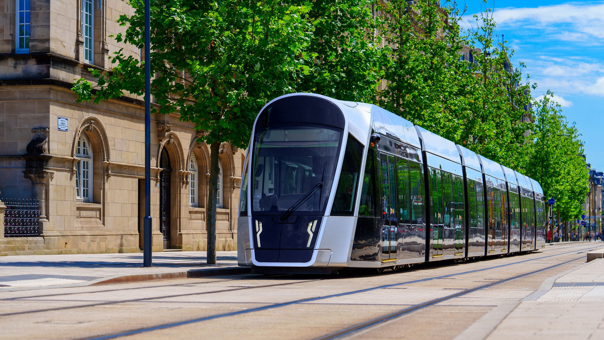Grey tram line in Luxembourg city with green trees