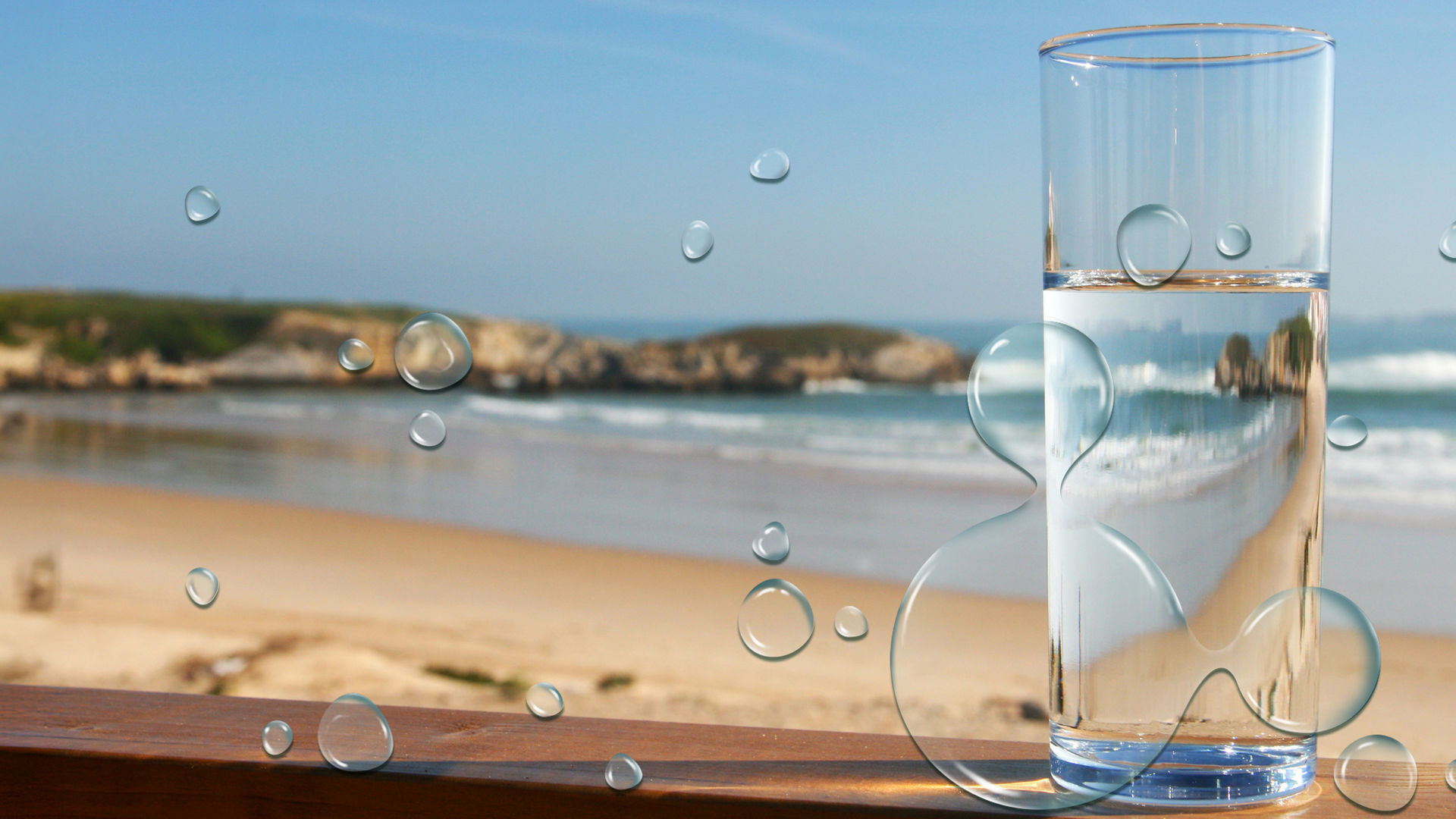 glass of water sitting by beach 