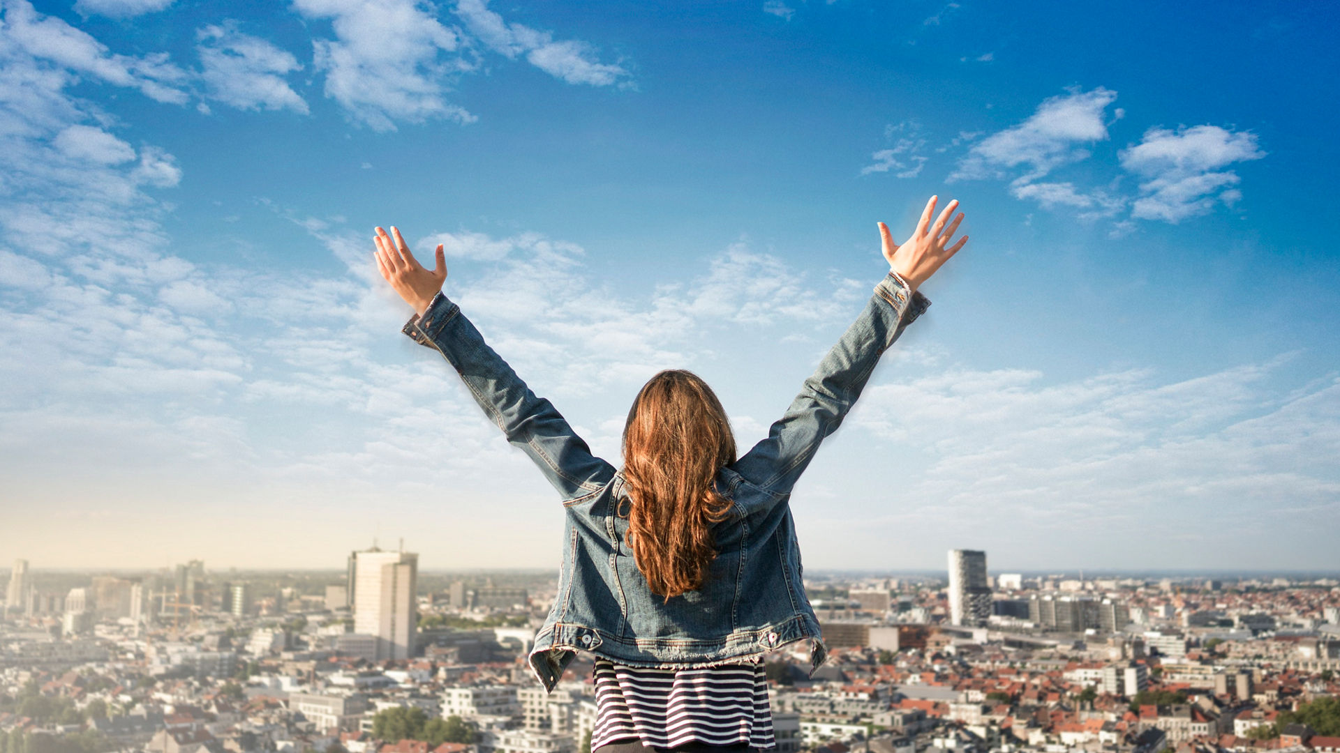 lady looking over city with hands in the air