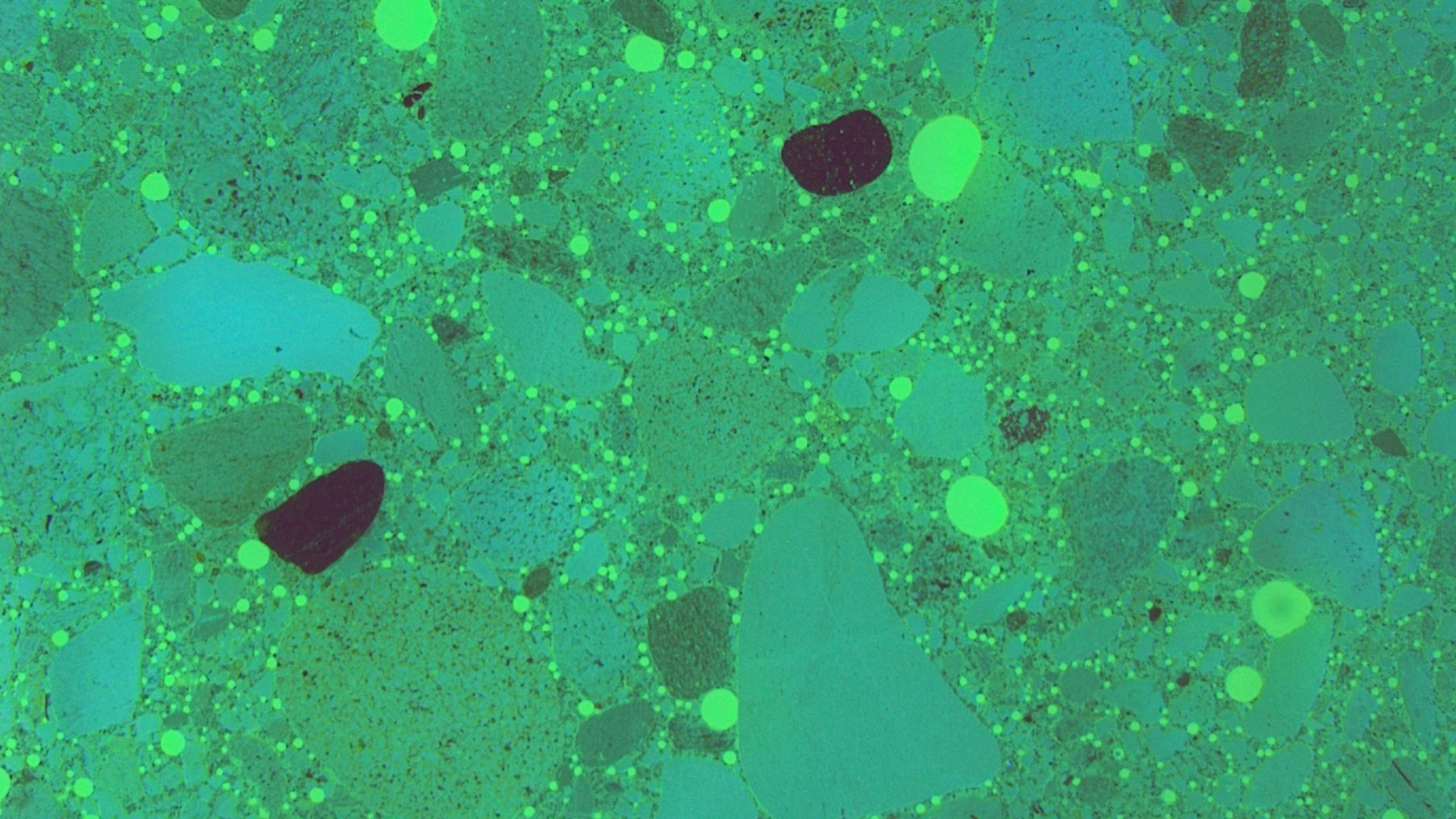 Thin slice of concrete under microscope in lab showing use of SikaControl AER air entrainer concrete admixture