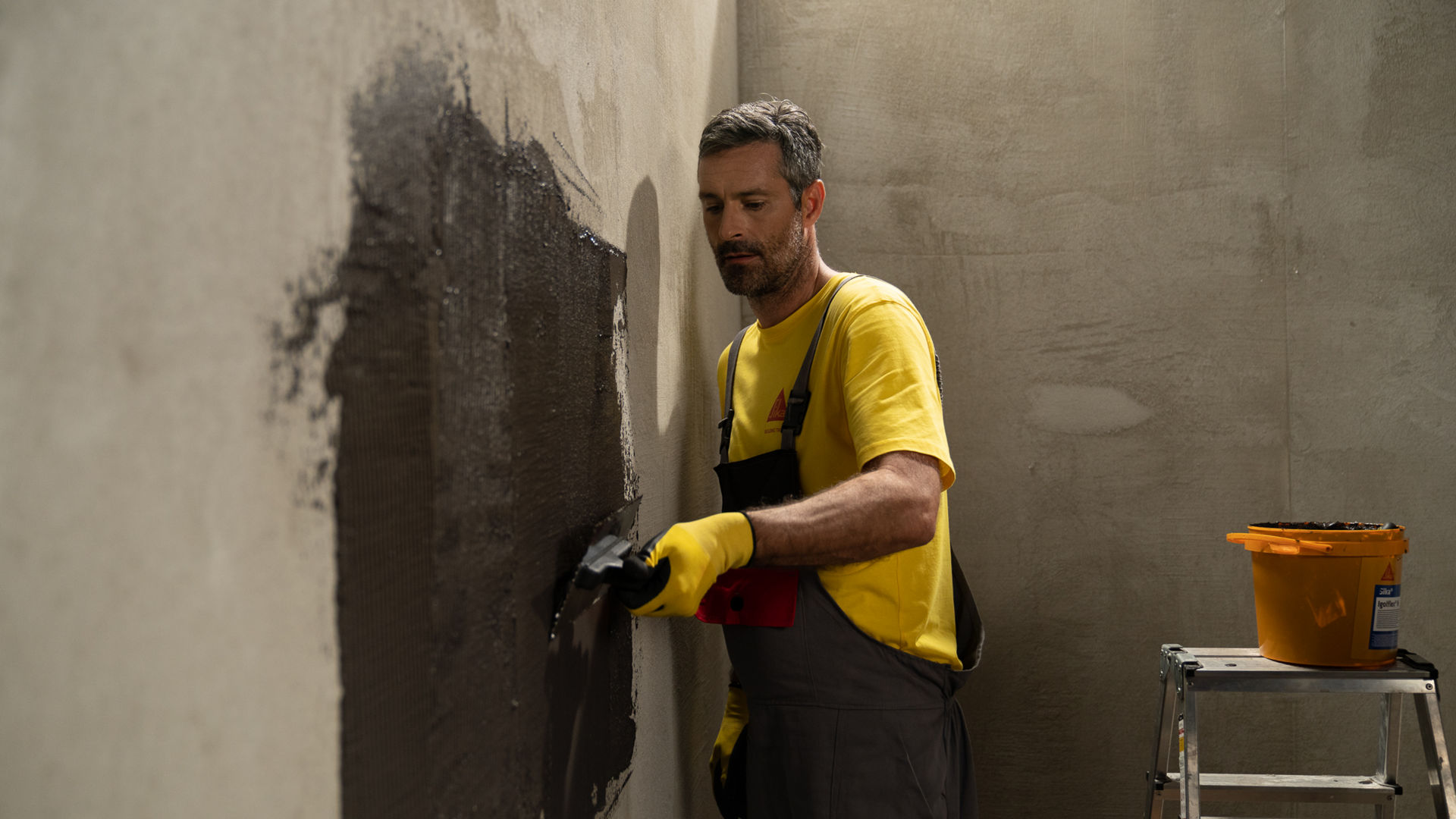 Man in yellow Sika tshirt applying Sika Igolflex-N waterproofing mortar