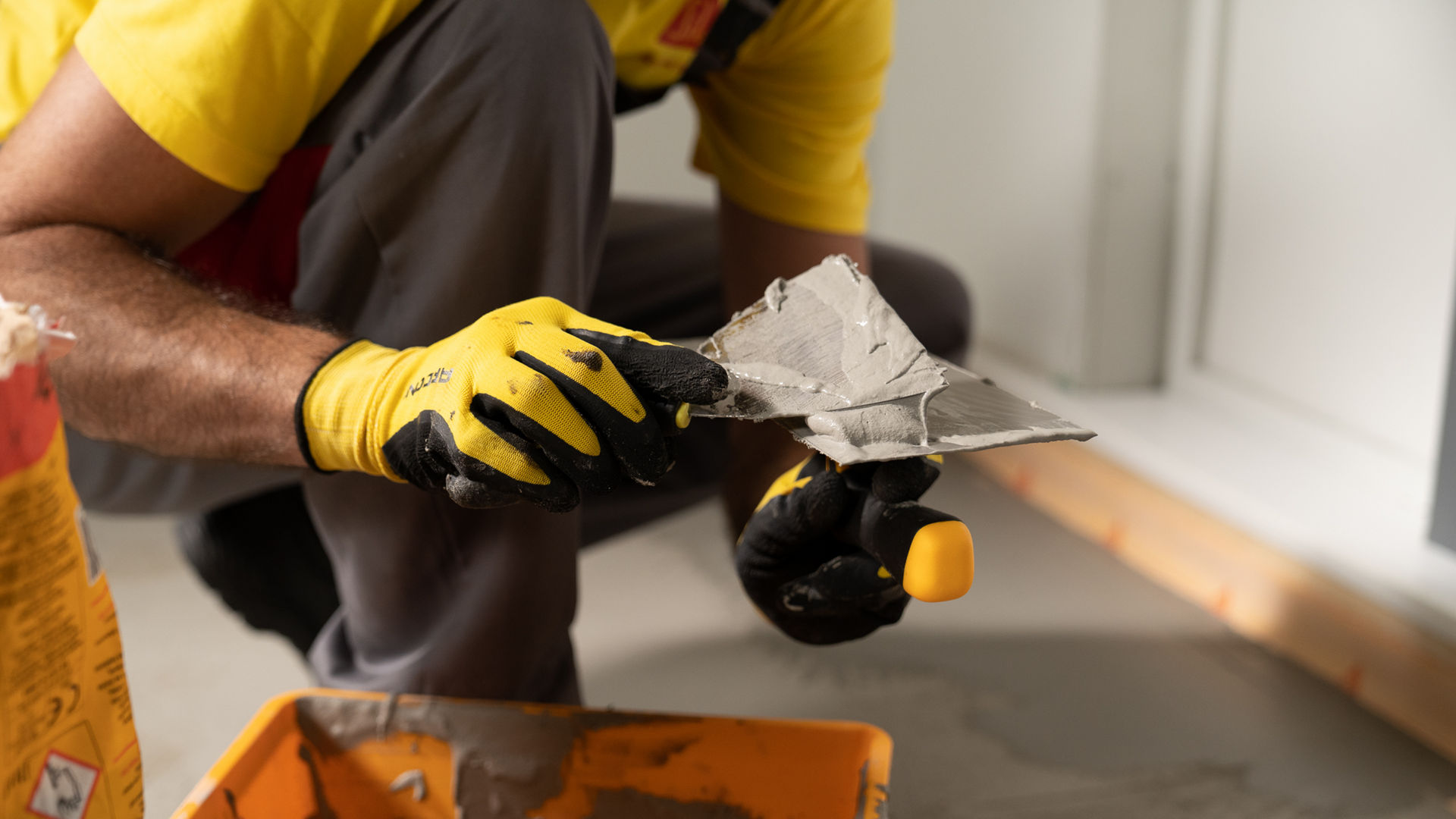 Man in yellow Sika tshirt applying Sika Igolflex-N waterproofing mortar with trowel