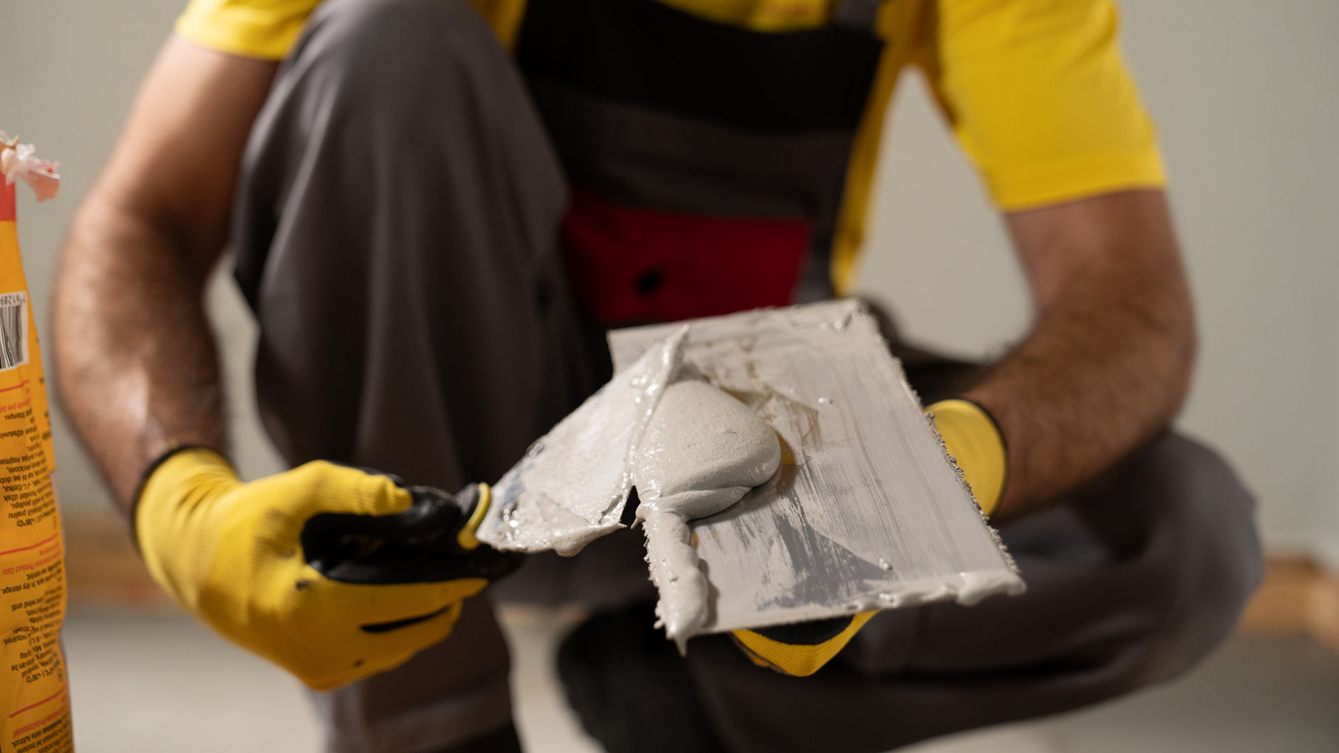 Man in yellow Sika tshirt applying Sika Igolflex-N waterproofing mortar with trowel