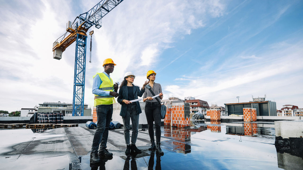 The photo shows three Sika employees on a rooftop at a construction site.