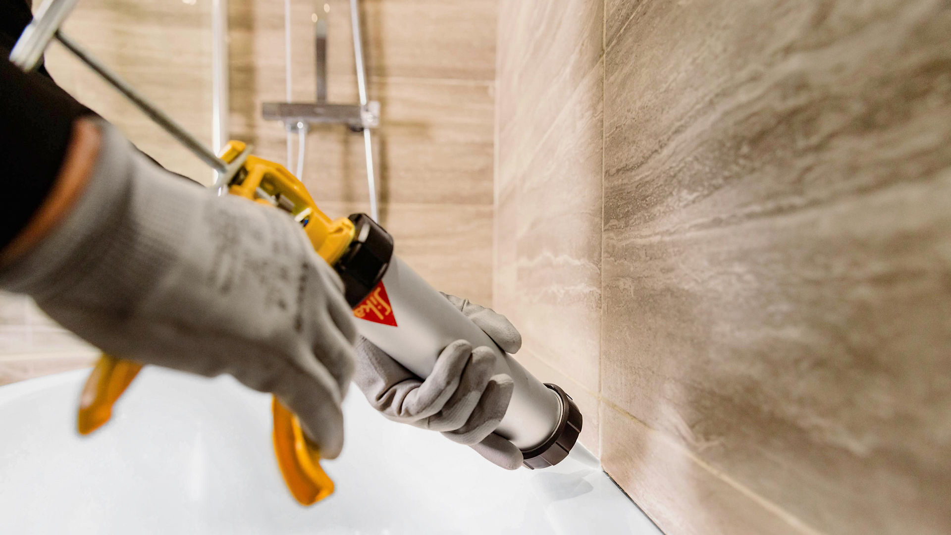 Applying sealant to bathtub edge in modern bathroom