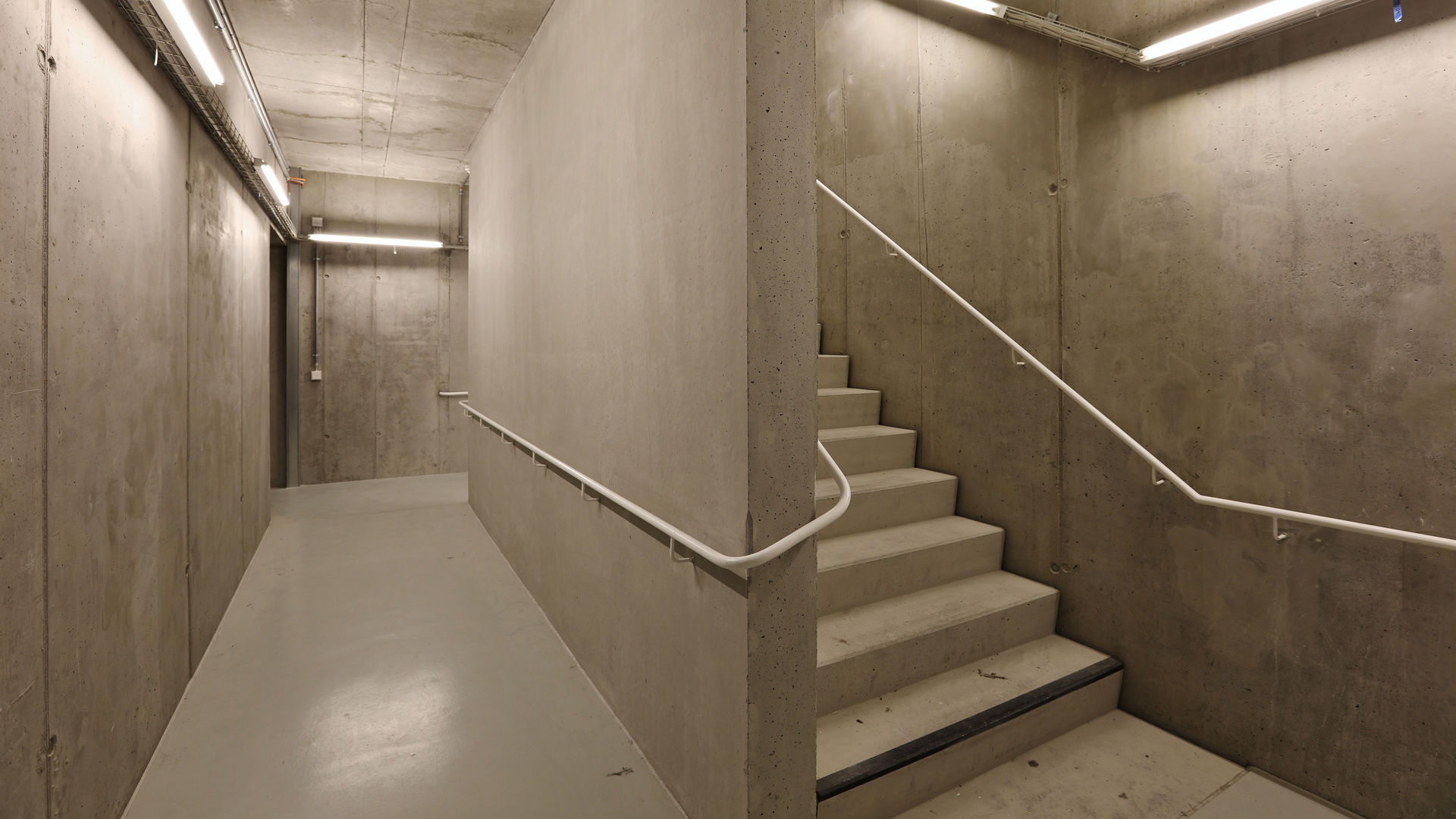 Concrete stairwell with lights in basement parking garage