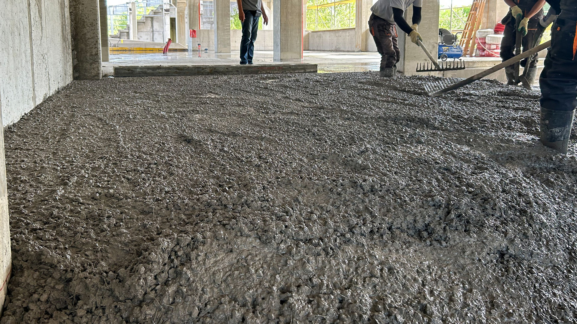 Construction workers leveling wet concrete floor