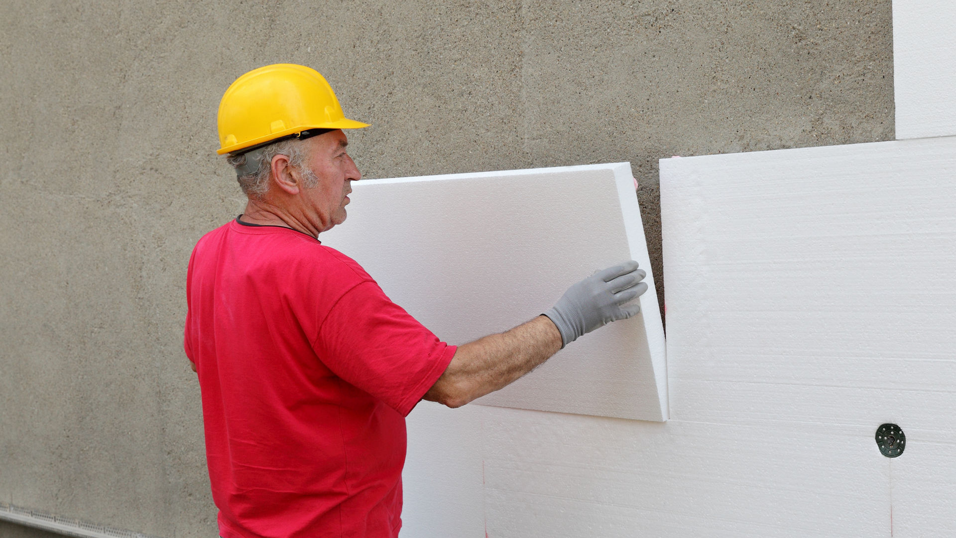 Worker installing insulation panels on wall