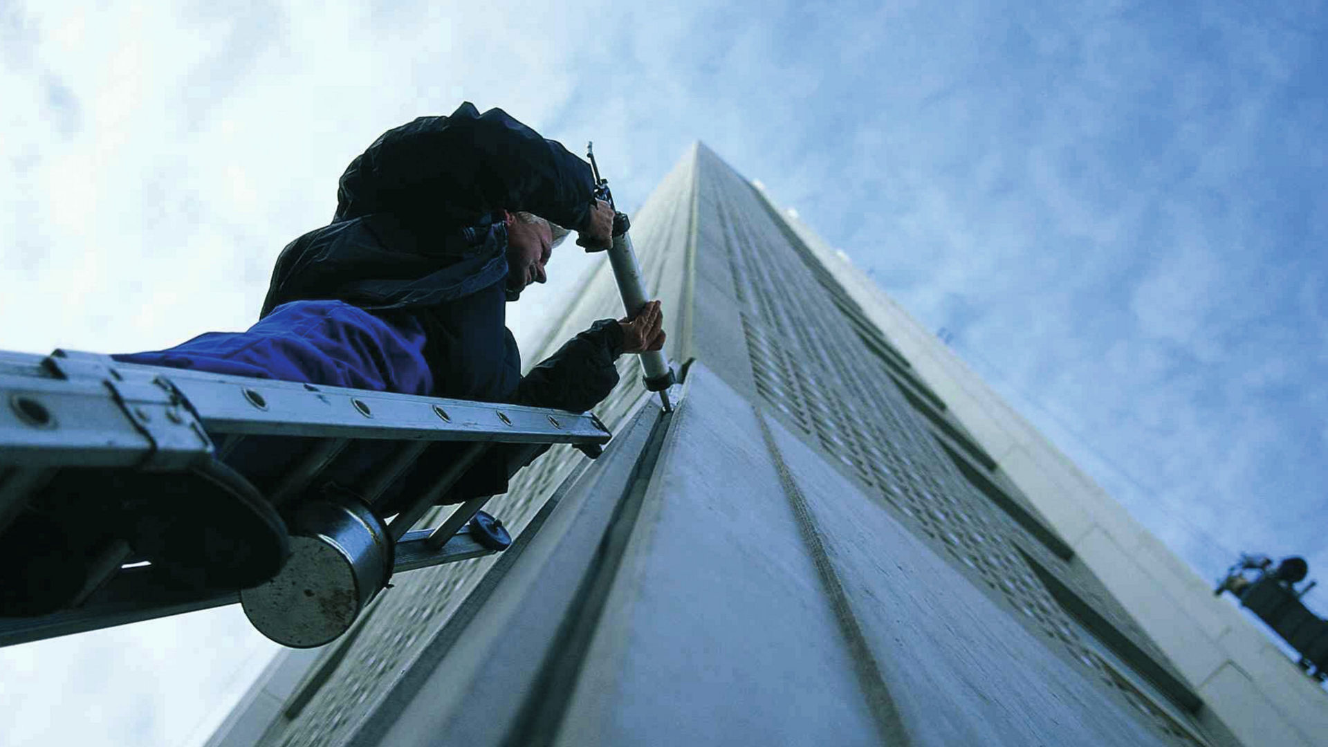 working on ladder sealing building facade