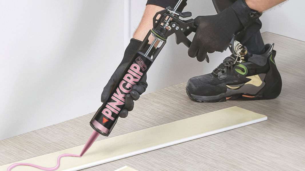 man applying sika pinkgrip adhesive to wood