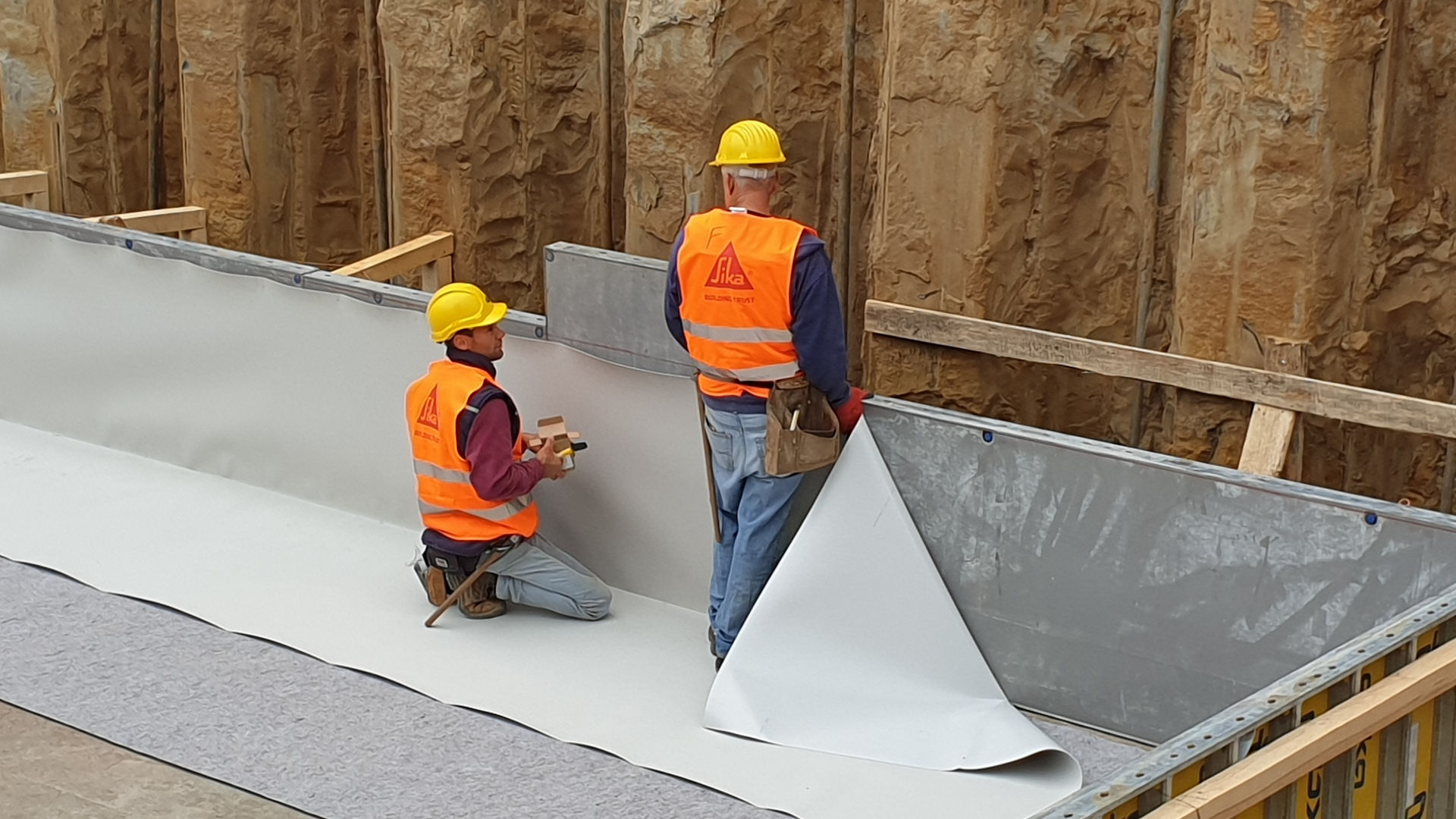 men applying waterproofing membrane to basement