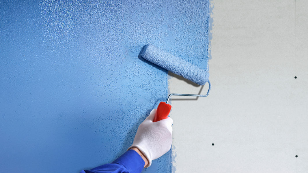 hand applying blue plaster bonding agent to wall