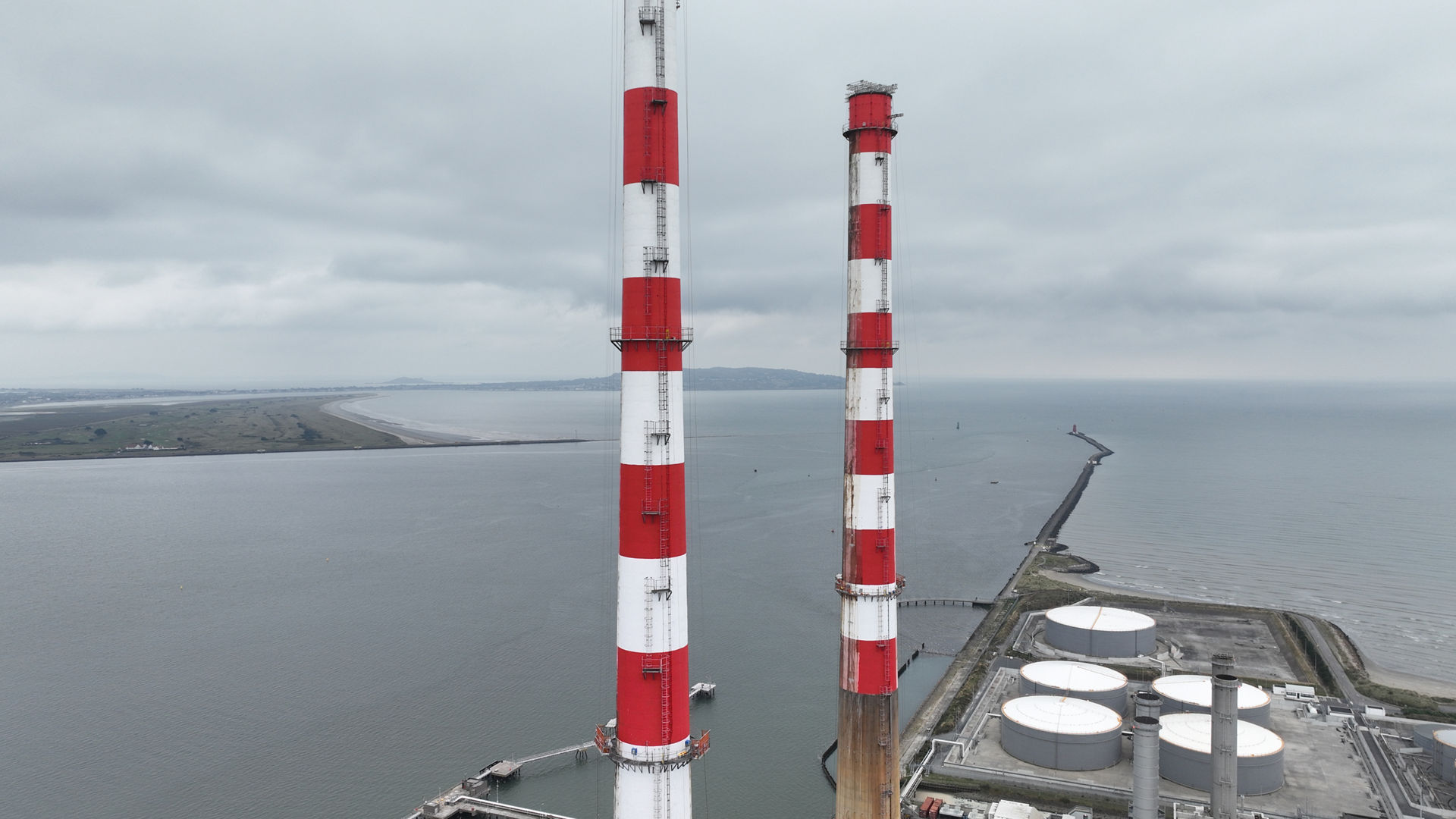 Red and white chimneys near industrial site