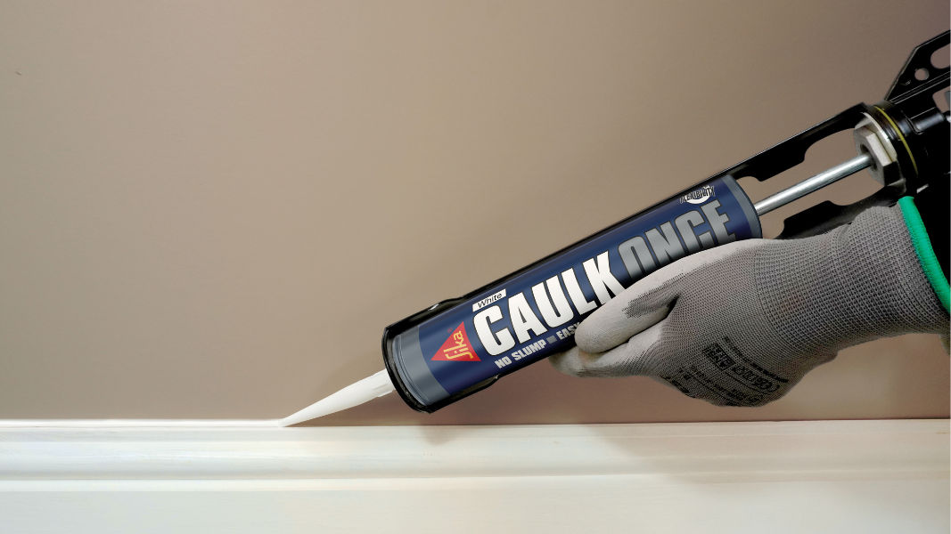 Hand applying caulk with caulking gun