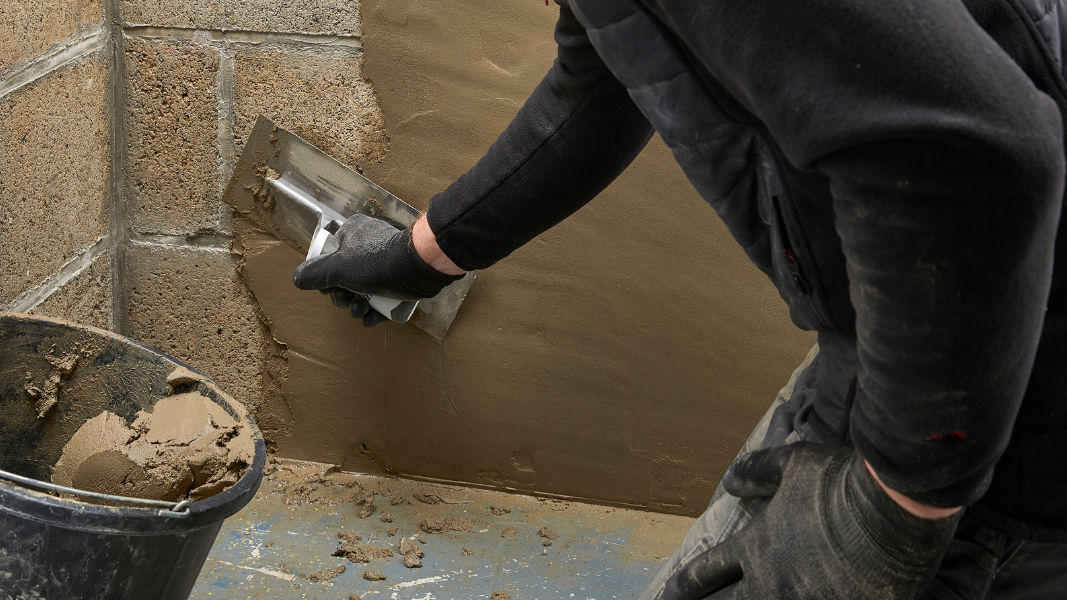 man applying waterproofing mortar to wall