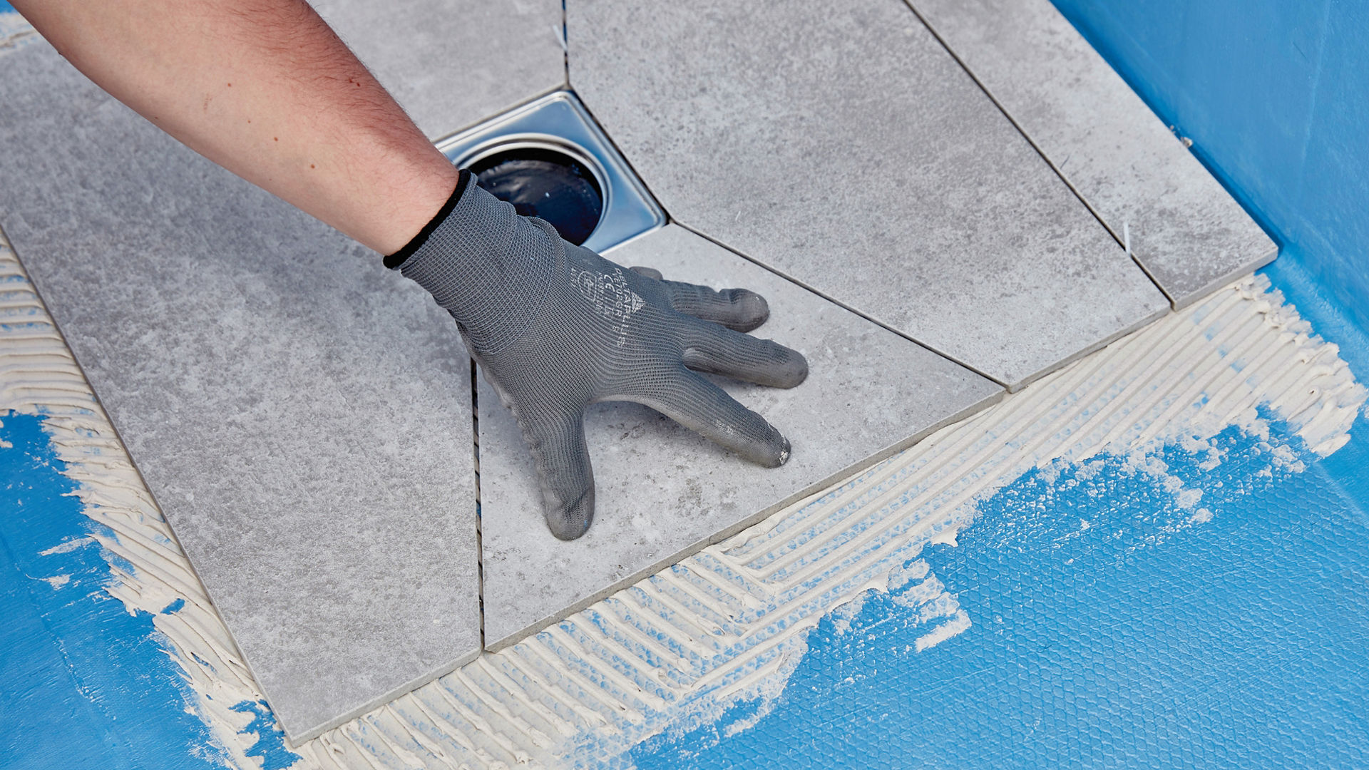 hand applying tiles to a wet room