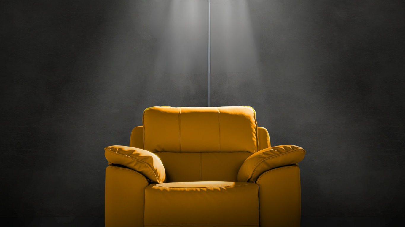 Yellow armchair under spotlight in dark room