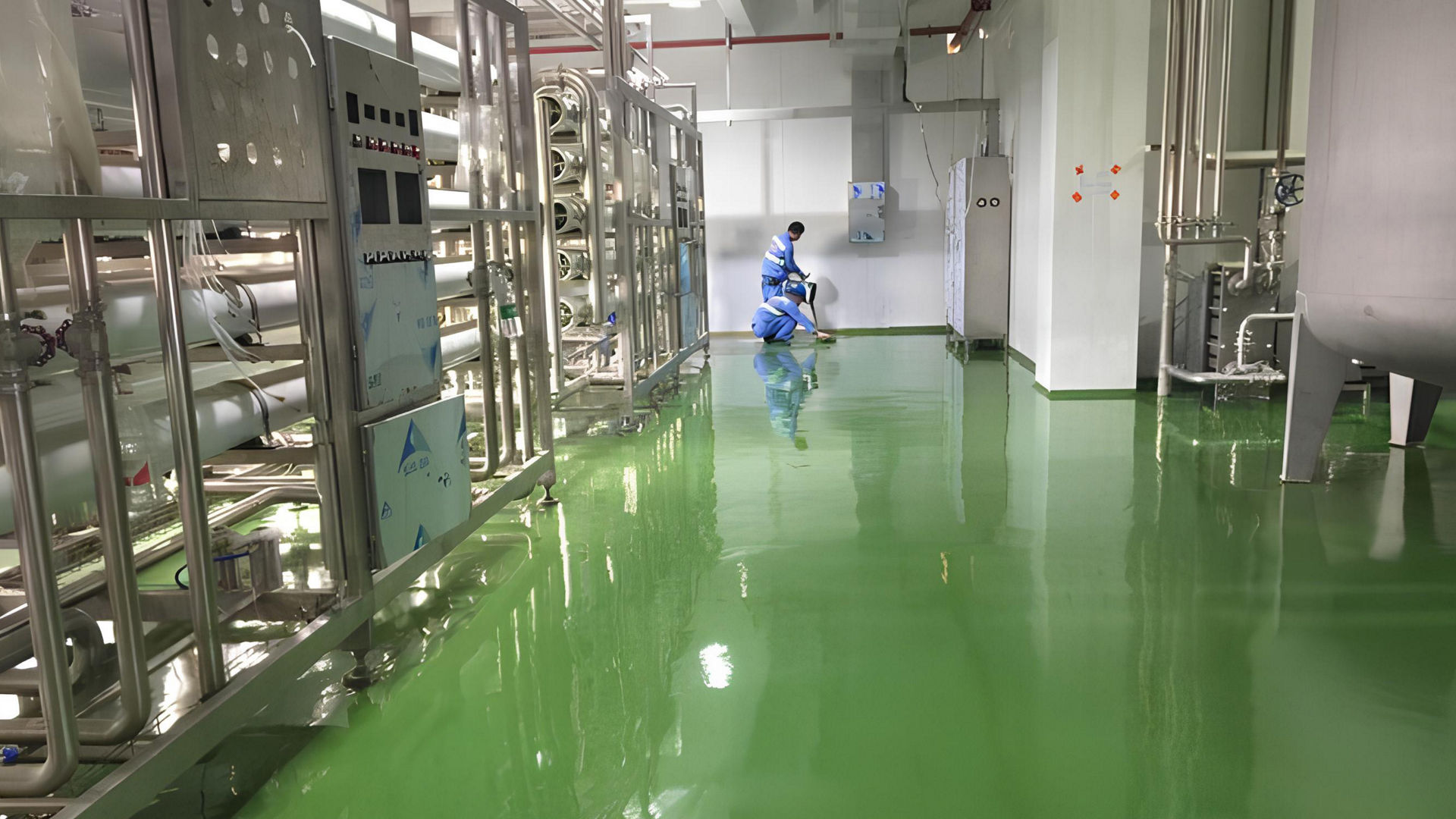 Industrial worker cleaning green factory floor