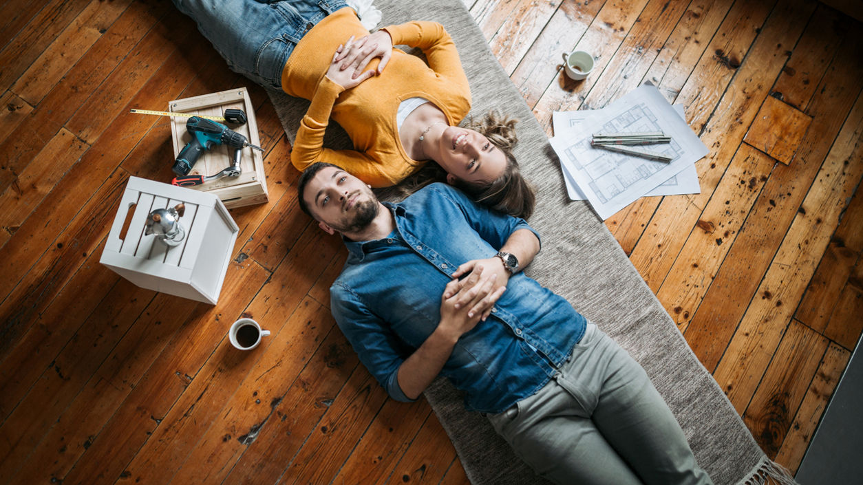 Young couple taking a break from painting and restoring their apartment by lying on the floor next to each other