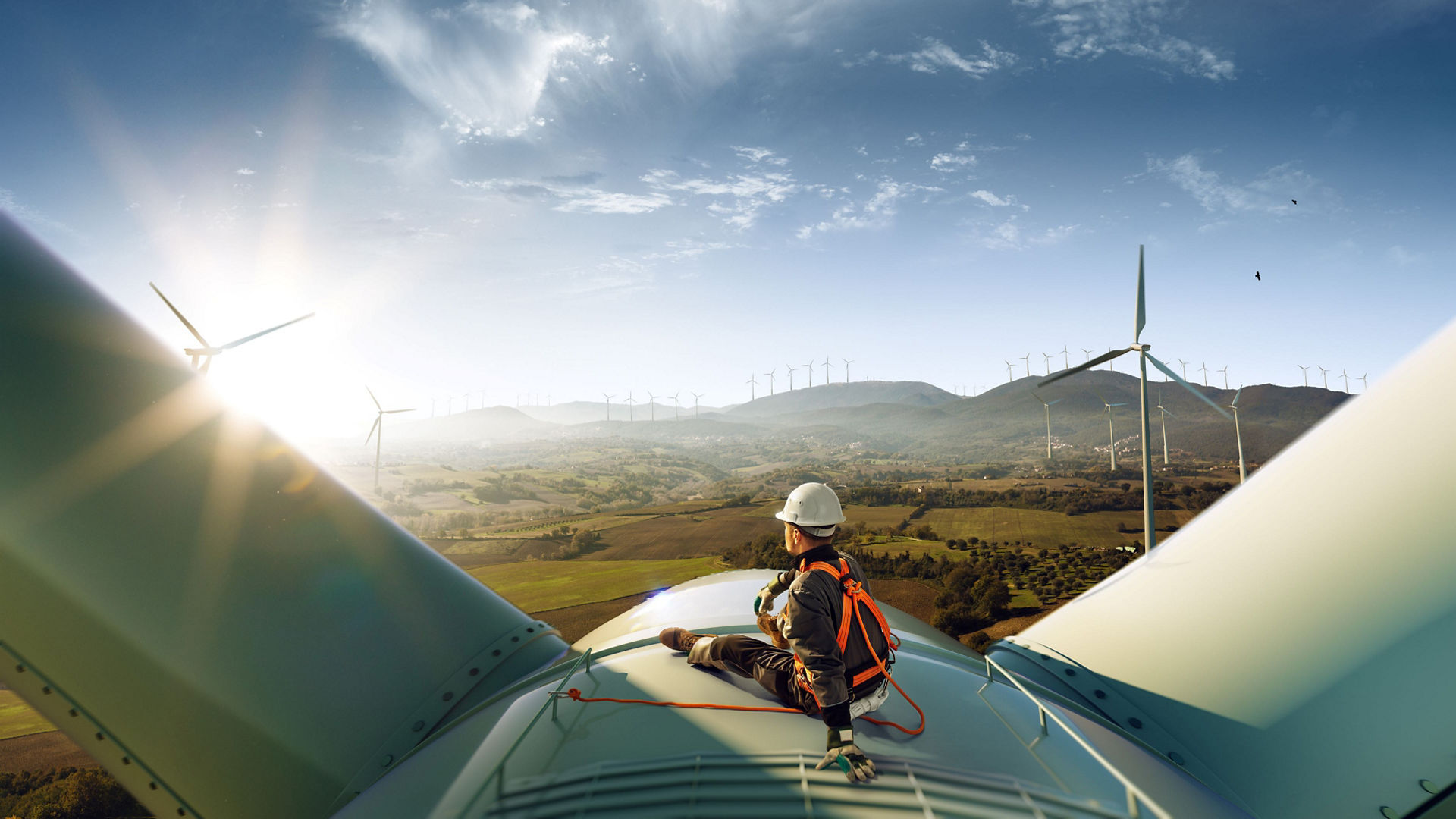 Worker sat on a wind turbine looking our to fields