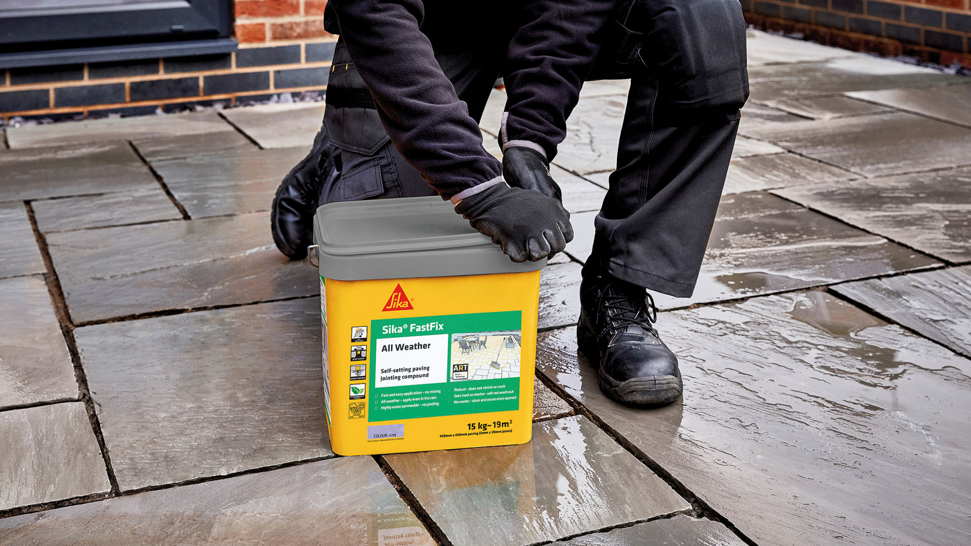 Paving outside with man opening tub of jointing compound