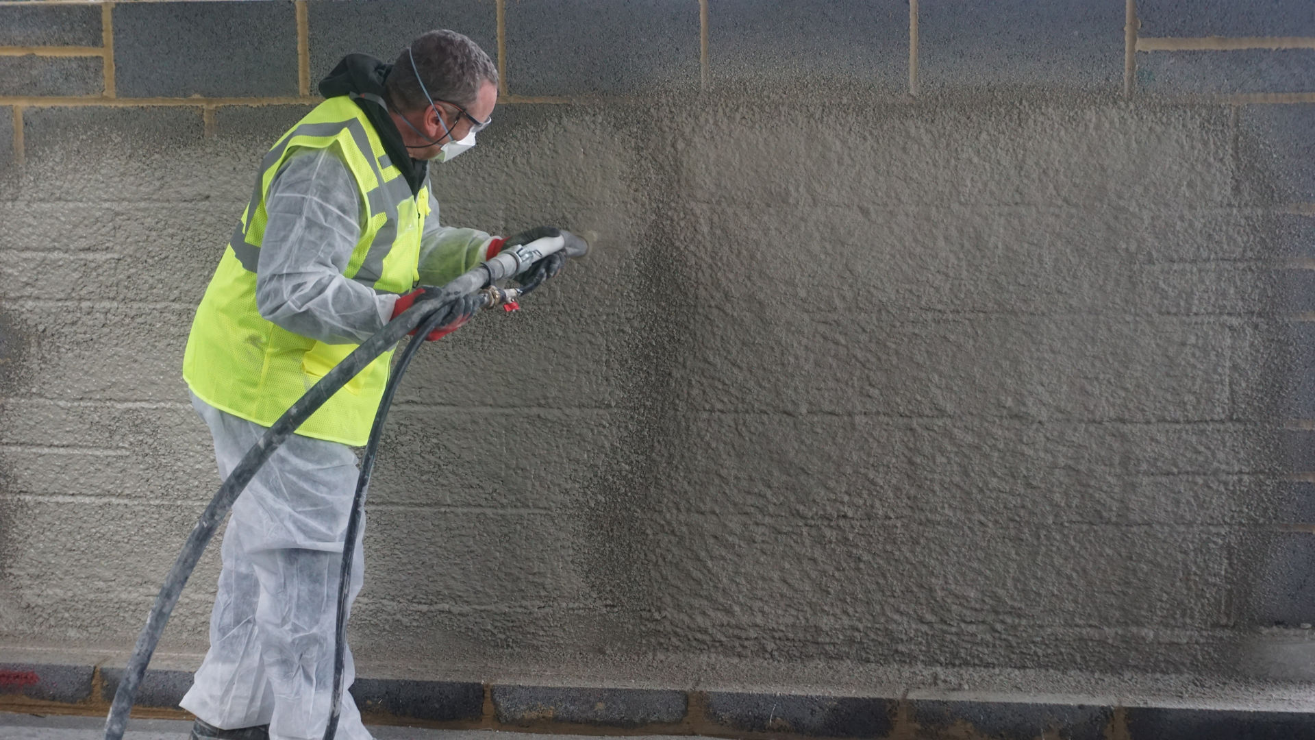 Application shot of Sika 1 LC Pre-bag Render being sprayed on to a wall. 