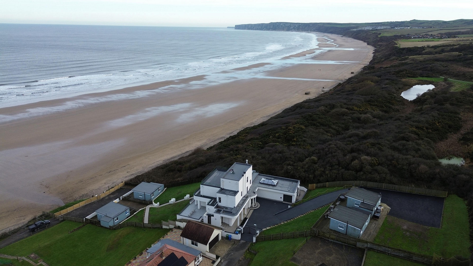 Coastal house overlooking expansive sandy beach and cliffs