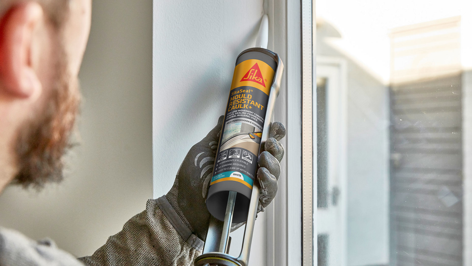 Person applying caulk around window frame