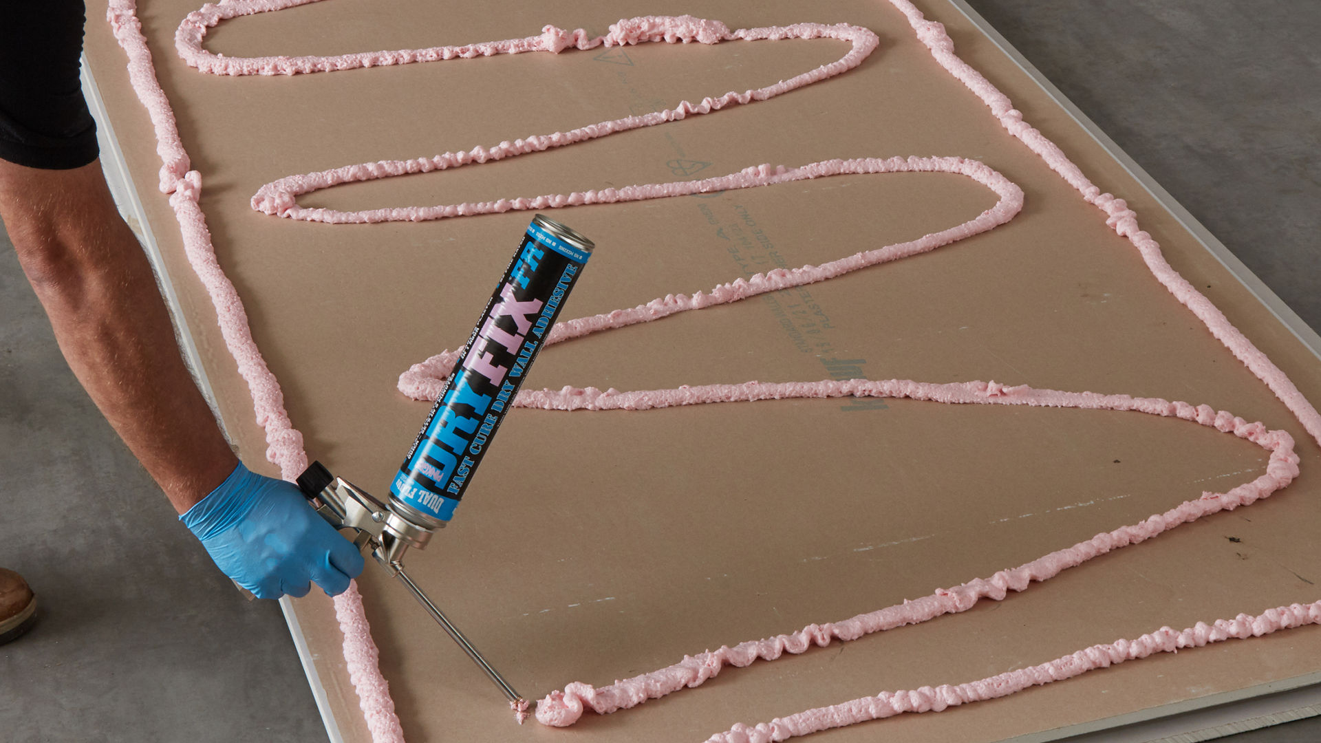 Person applying Dryfix adhesive to plasterboard