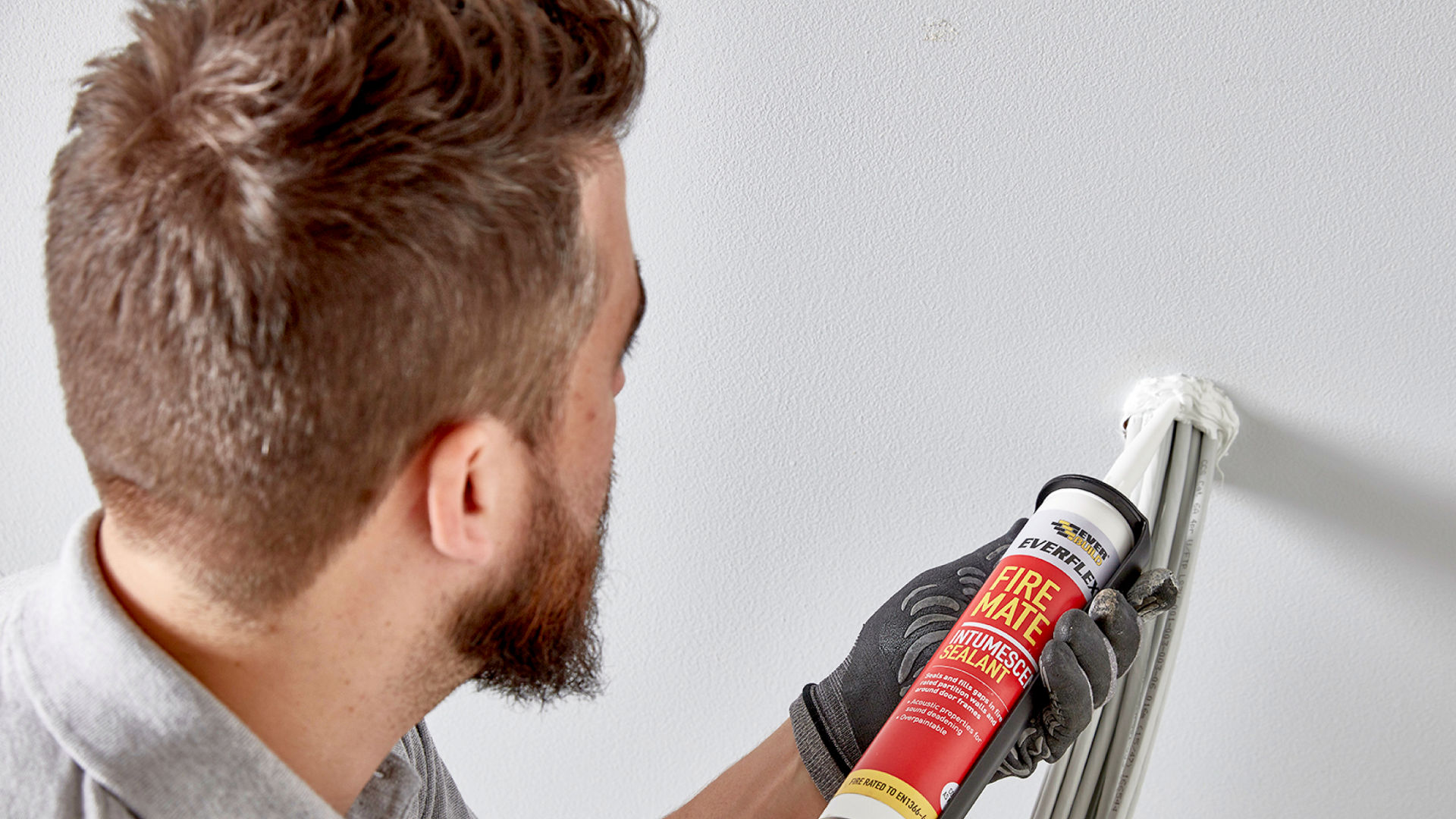 Man applying Fire Mate sealant to cables in wall