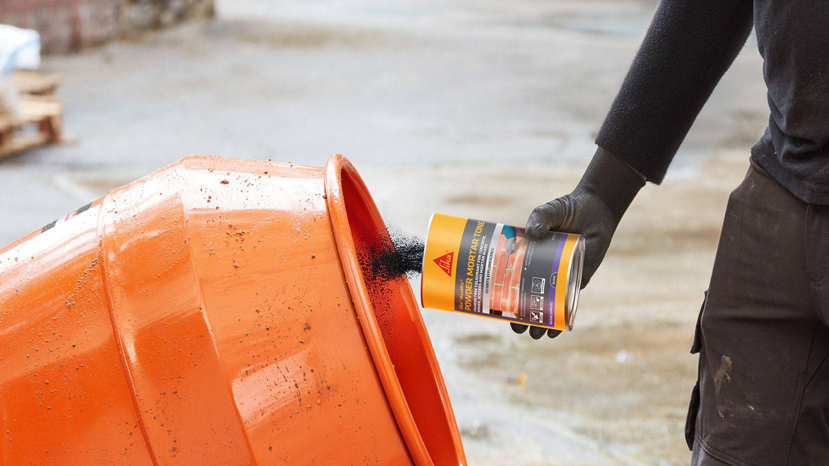 Worker adding powder to orange cement mixer