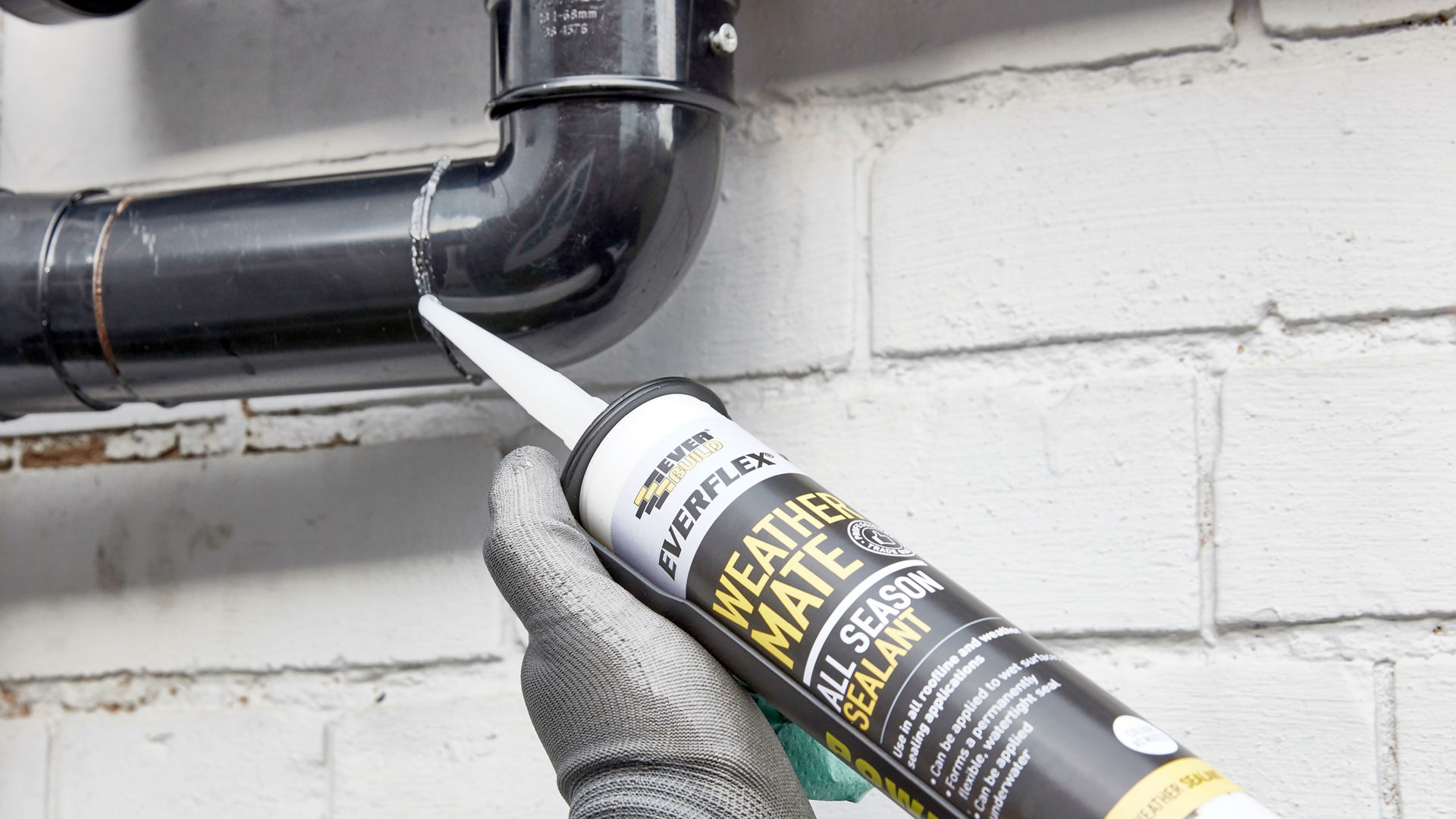 Black sealant being applied to drain pipe