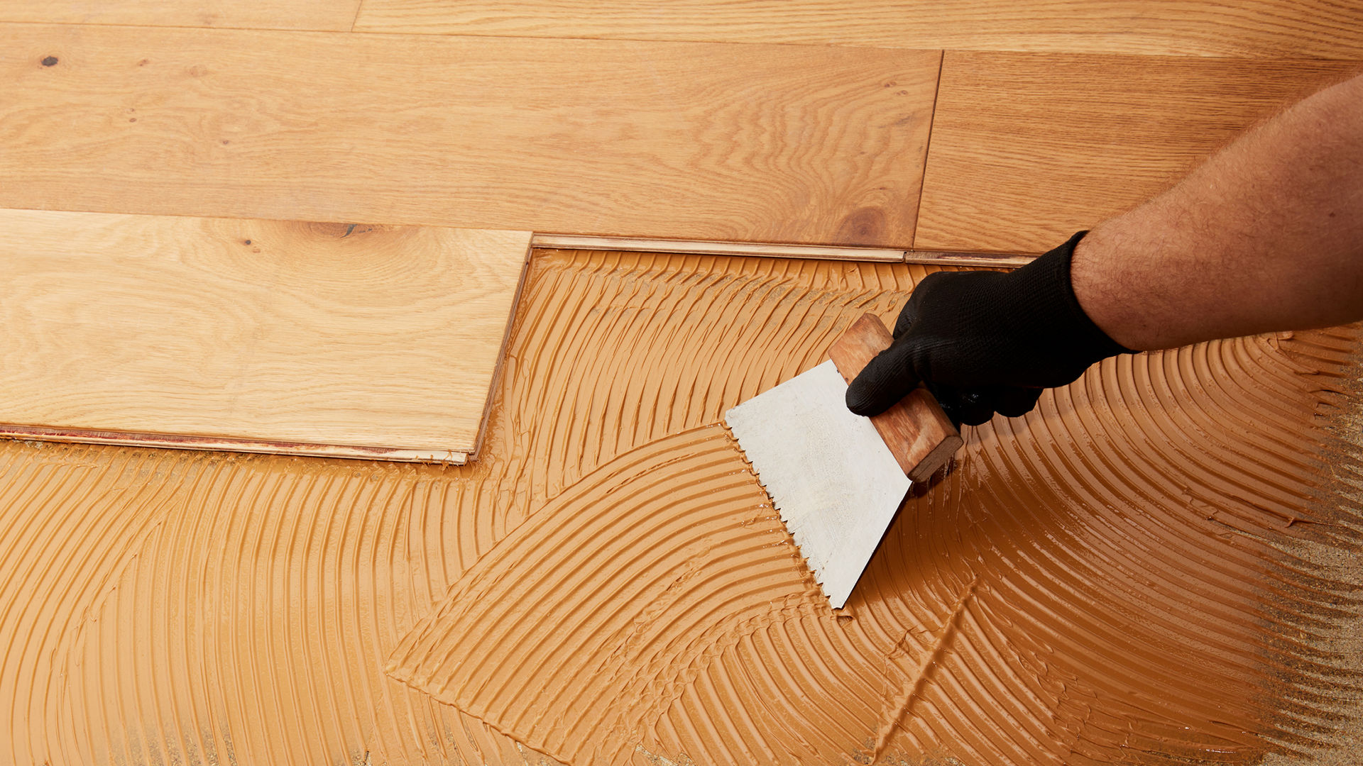 Person applying flooring adhesive to floor