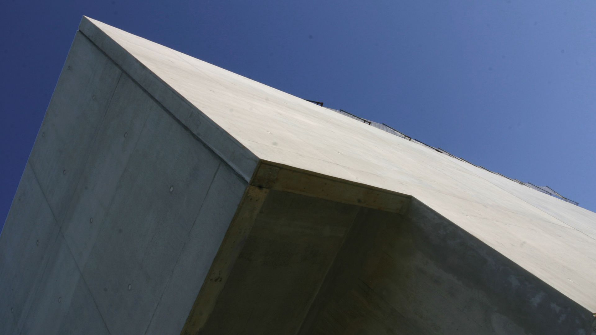 Rigid bonding of prefabricated concrete facade panels to building with architectural smooth concrete and blue sky