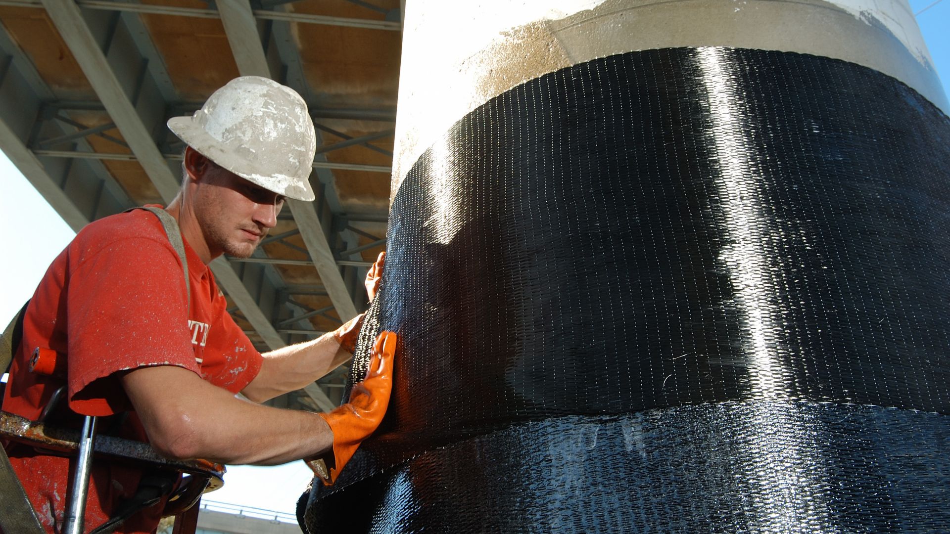 Men applying Sika CarboDur carbon fiber plates for structural strengthening